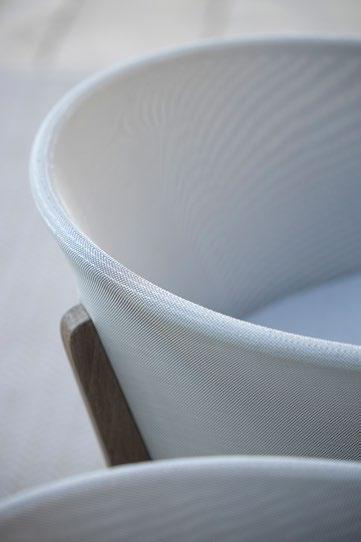 Close-up of a white fabric lampshade with a subtle texture, partially framed by a wooden support on a light background.